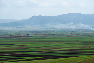 Fototapeta premium Vibrant green meadow and agricultural fields at springtime in Transylvania, Romania.