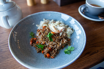 Delicious buckwheat porridge with sauce and parsley in a blue plate