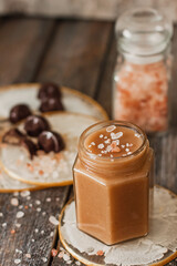 Homemade salted caramel sauce in jar on vintage background