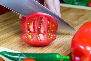 Chef cuts tomatoes into pieces on a cutting Board