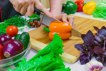 Chef cuts orange paprika on a cutting Board