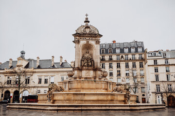 Roman Catholic Church of Saint-Sulpice in Paris, France. Cathedral was founded in 1646. Square with fountain in front of facade. Sculptures of saints and lions adorn fountain.