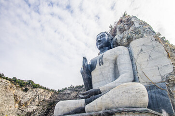 Large Buddha statue in front of a stone-cut mountain