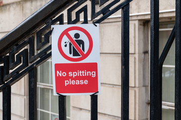 No spitting sign attached to black railings