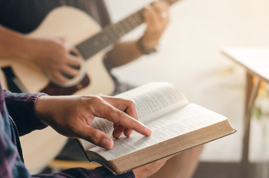 A Young Boy Sat And Read The Bible While His Friend Played Guitar At Church When He Worshiped God. A Small Group Of Christians Or A Concept In A Church At A Church