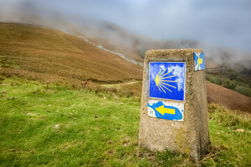 RONCESVALLES, SPAIN - The Way Marking Post with Scallop Shell Symbol and Yellow Arrow Sign in the...