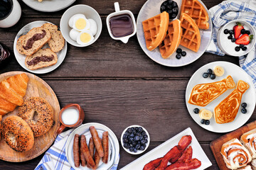 Fathers Day breakfast frame. Top down view on a dark wood background. Tie pancakes, mustache toast and assorted dad themed food.