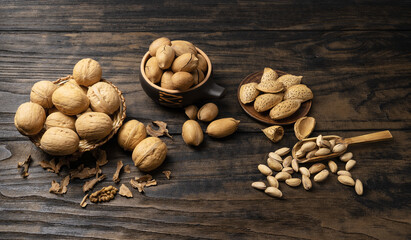 whole walnuts in a basket, pecans, almonds and pistachios on a rustic old wooden table.
