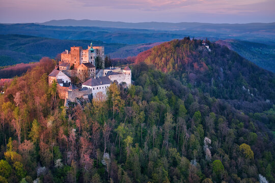 Aerial view on Buchlov Castle, one of the most important castles in Moravia. Monumental castle in Romanesque Gothic style, standing on a wooded hill, lit by reddish light of setting sun. Czech castles