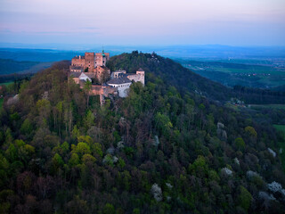 Fototapeta na wymiar Buchlov Castle. Aerial view on monumental castle in Romanesque Gothic style, standing on a wooded hill against Saint Barbara’s Chapel on the hill in background. Spring, tourism hot spot. Czech castles