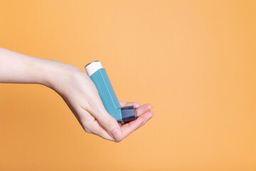 Hand holds inhaler to treat asthma. World Asthma Day. Concept of allergy care. Copy space