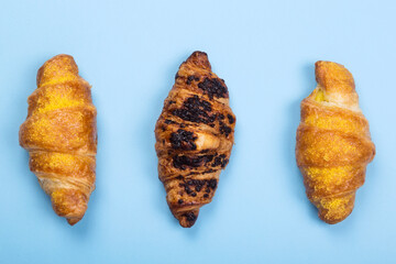 Various croissants (with chocolate and lemon cream) on blue background. Top view
