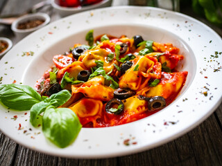 Tortelloni stuffed with prosciutto ham and vegetables on wooden table

