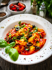 Tortelloni stuffed with prosciutto ham and vegetables on wooden table
