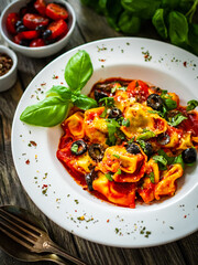 Tortelloni stuffed with prosciutto ham and vegetables on wooden table
