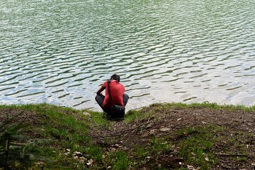 man squats at the rippling water surface