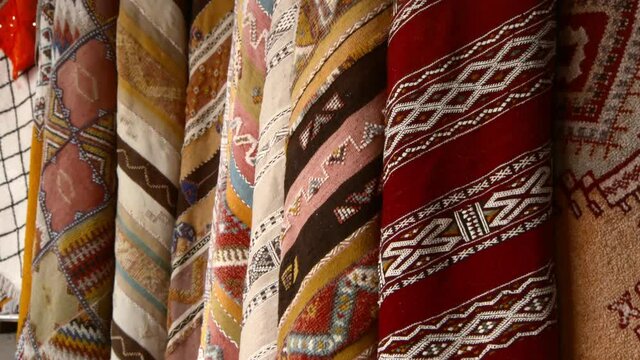 Close-Up Pan Of A Large Collection Of Carpets And Textiles Hanging On Display At A Market, With Vibrant Colors And Weaves - Casablanca, Morocco