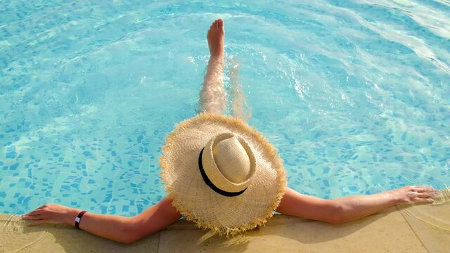 Woman with hat in the pool. Selective focus.