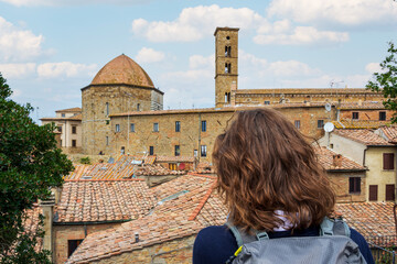 Tuscany, Volterra town skyline, girl admiring skyline and panorama view of the old Etruscan and medieval city. Pisa, Italy.
