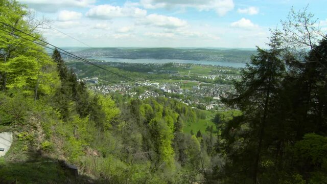 Lockdown Of A Lush Green Hillside On A Sunny Day With Gondola Cables, Rolling Hills, And The Swiss Countryside Extending Into The Horizon - Zurich, Switzerland