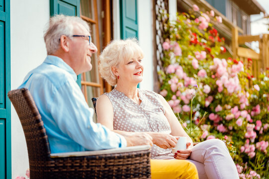Senior couple enjoying their coffee on porch in front of their house