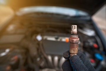 Man hold in hand faulty old oxygen sensor of exhaust system, car stalled, fault in emission system,...