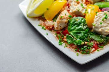 Cooked chicken breast pieces with peppers, sugar snap peas, and baby leaf spinach in a spicy sweet and sour sauce with fragrant rice