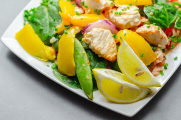 Cooked chicken breast pieces with peppers, sugar snap peas, and baby leaf spinach in a spicy sweet and sour sauce with fragrant rice