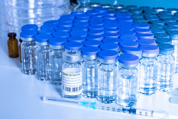 Glass bottle vial and syringe with Covid-19 Coronavirus vaccine in a research medical facility lab. Ampoules with cure on the medical worker laboratory table. Sars-cov-2 pandemic concept.