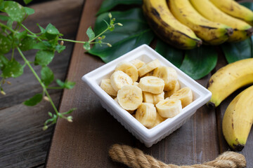 Cut bananas in the plate on wooden background.