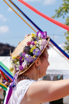 Traditional English maypole dancer with flower straw hat holding colourful maypole ribbons