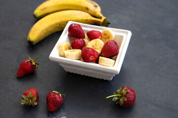 Fresh banana and strawberry on wooden background.