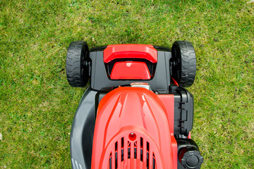 Fototapeta premium lawnmower on grass. Lawn mower across a green lawn. Mow the lawn for a green lawn 