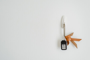 Car key, key chain made from lather to be fish hanging on hook at the whit wall in home or apartment with copy space.