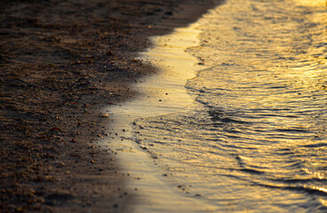 Waves on a sandy beach at sunset