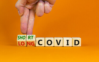 Long covid symbol. Doctor turnes wooden cubes and changes words 'short covid' to 'long covid'. Beautiful orange background, copy space. Medical, covid-19 pandemic long covid concept.