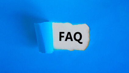 FAQ, frequently asked questions symbol. Concept words 'FAQ, frequently asked questions' appearing behind torn blue paper. Beautiful blue background, copy space. Business and FAQ concept.