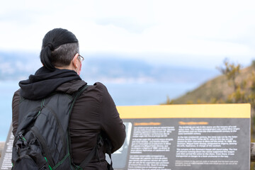 Woman with protective face mask reads an information sign on a hiking trail.