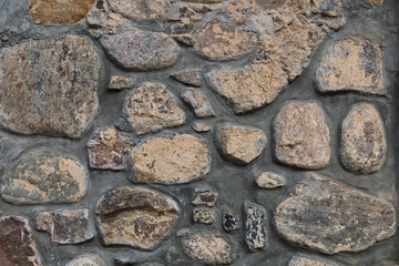 Grey dark stone wall. Uneven rock surface, decorative vintage tile of weathered facade building. Rock gray background. Natural textured backdrop, element of design. 