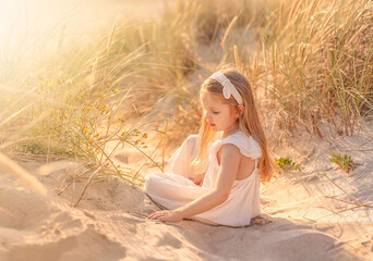 Beautiful little girl with long hair at the beach in summer. Summer vacations with kids concept.