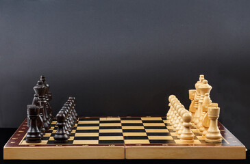 Wooden chess. Chess pieces are located on a chessboard on a black background. Close-up. Full depth of field.