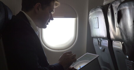 Young businessman working with pad in plane