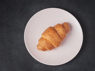 baked french croissants on a brown kitchen board, black background, close-up