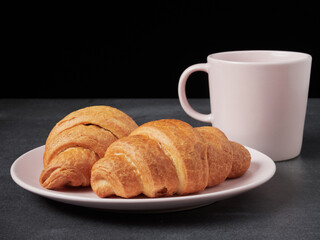 baked french croissants on a brown kitchen board, black background, close-up