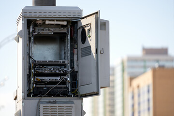 The case of the cellular base station unit with an open door on the background of high-rise...