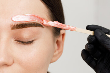 Makeup artist does facial hair removal procedure. Styling and lamination of eyebrows. Woman doing...