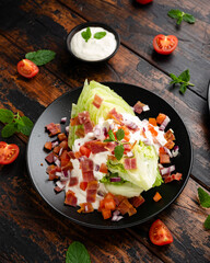 Iceberg wedge salad with bacon, cherry tomatoes, red onion and dressing. healthy food