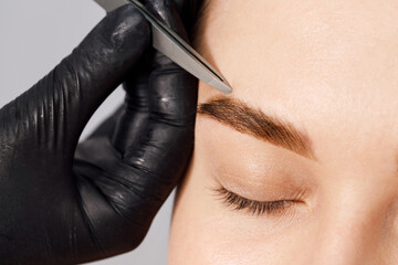 Styling and lamination of eyebrows. Woman doing eyebrow permanent makeup correction. Female...