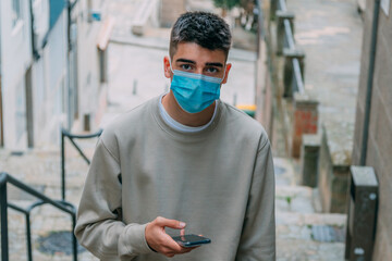 teenage boy with mask and mobile phone on the street
