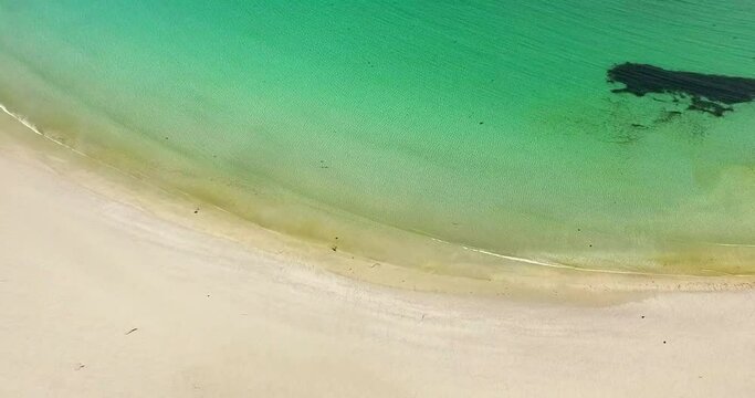 Aerial Panning Bright Sand And Gentle Waves Along Remote Shoreline With Turquoise Colored Water And Sunlight Reflected Off The Ocean Surface Ripples - Isle of Tiree, United Kingdom